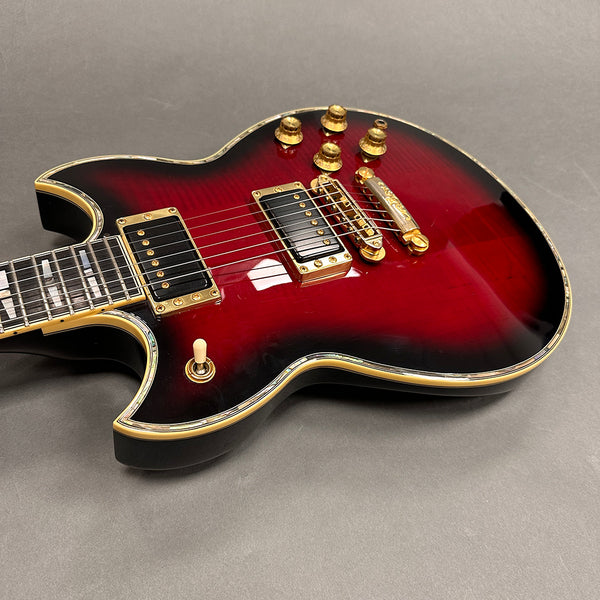 Electric guitar with red sunburst finish, gold hardware, dual humbucker pickups, and cream binding on a gray background