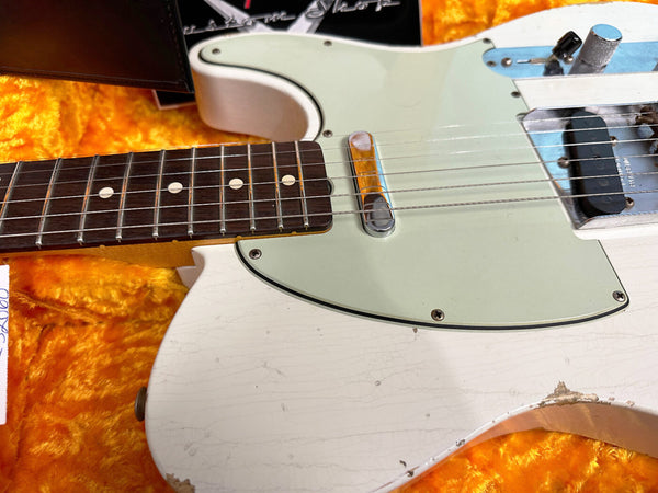 Close-up of vintage white electric guitar body and fretboard with visible wear and cracks on an orange plush case interior