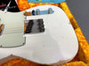 Close-up of vintage white Fender Telecaster electric guitar body showing aged finish, chrome hardware, and wear marks in orange plush guitar case