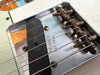 Close-up image of vintage Fender Telecaster bridge and single-coil pickup with strings and adjustable saddles showing wear and patina
