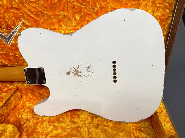 Back of vintage white Fender Telecaster electric guitar with worn and chipped finish resting in orange plush-lined guitar case