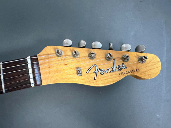 Close-up of Fender Telecaster guitar headstock with tuning pegs and logo on natural wood finish