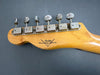 Close-up of vintage Fender Custom Shop guitar headstock with six metal tuning pegs on natural wood finish against dark background