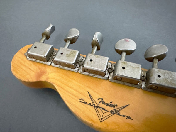 Close-up of vintage Fender Custom Shop guitar headstock showing aged tuning pegs and logo on natural wood finish