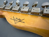 Close-up of vintage Fender Custom Shop guitar headstock with six worn tuning pegs and logo on natural wood finish