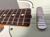 Close-up of electric guitar fretboard and chrome pickup cover with metal strings and dot inlays on dark wood fingerboard