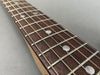 Close-up of rosewood guitar fretboard with metal frets and silver strings on gray background