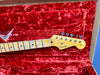 Fender Stratocaster guitar headstock with maple neck and vintage tuners on red plush case lining