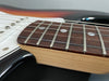 Close-up of electric guitar rosewood fretboard with dot inlays and maple neck on black body with white pickguard
