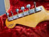 Close-up of Fender Custom Shop Guitar maple neck headstock with vintage tuning pegs on red plush guitar case interior