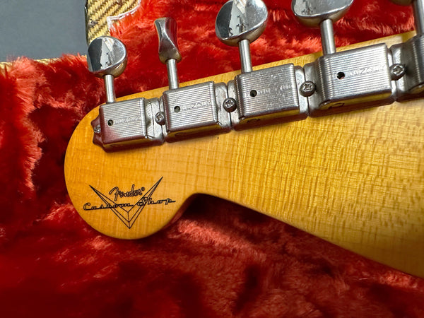 Close-up of Fender Custom Shop electric guitar headstock with vintage tuning machines on red plush guitar case interior