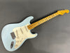 Fender Stratocaster electric guitar with light blue finish and maple fretboard laid flat on gray background