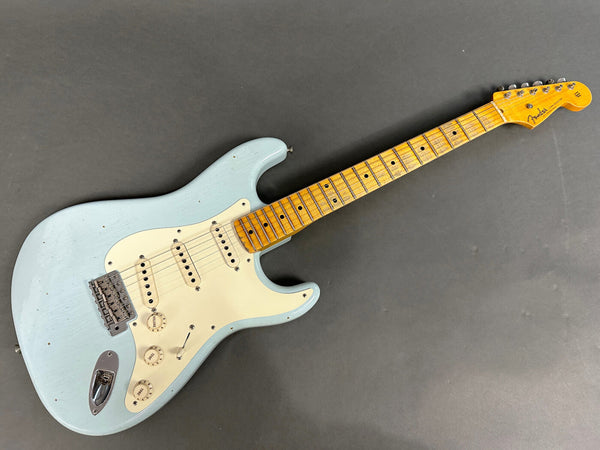 Fender Stratocaster electric guitar with light blue finish and maple fretboard laid flat on gray background