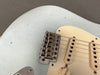 Close-up of vintage Fender stratocaster electric guitar bridge and pickups with light blue relic finish and cream pickguard