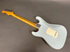 Rear view of light blue electric guitar with maple neck and vintage-style tuning pegs on grey background