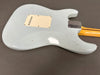 Back view of light blue electric guitar body with cream plastic backplate and worn finish showing aging and small paint chips, attached maple neck with metal neck plate on gray background