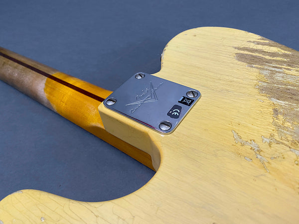 Close-up of vintage Fender electric guitar neck plate and worn cream body showing wood grain and aged finish