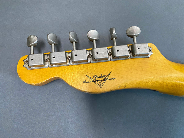 Vintage Fender Custom Shop guitar headstock with six metal tuning pegs on gray background