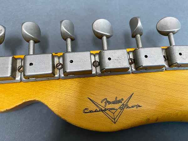 Close-up of vintage Fender Custom Shop guitar headstock with metal tuning pegs and logo on yellow wood finish