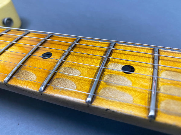Close-up of worn maple guitar fretboard with metal frets and black dot position markers on electric guitar neck