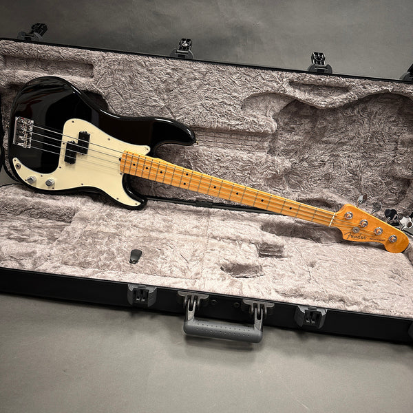 Fender Precision Bass guitar with black body and maple neck lying in open hardshell guitar case with plush gray interior lining