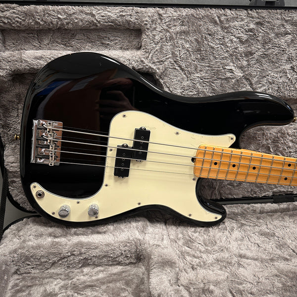 Black electric bass guitar with white pickguard and maple fretboard in a gray plush guitar case