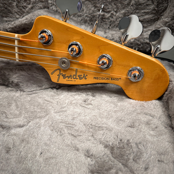 Close-up of Fender Precision Bass headstock with tuning pegs and strings on soft grey case lining