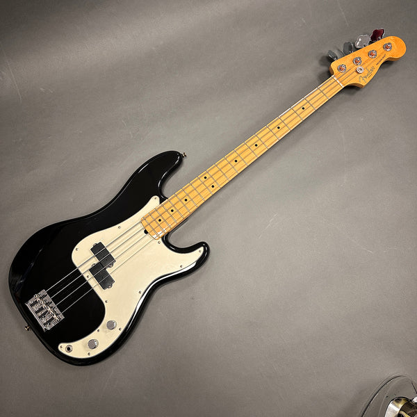 Fender Precision Bass electric guitar with black body, maple neck, white pickguard, and chrome hardware on gray background