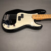 Black electric bass guitar with maple neck and white pickguard on grey background