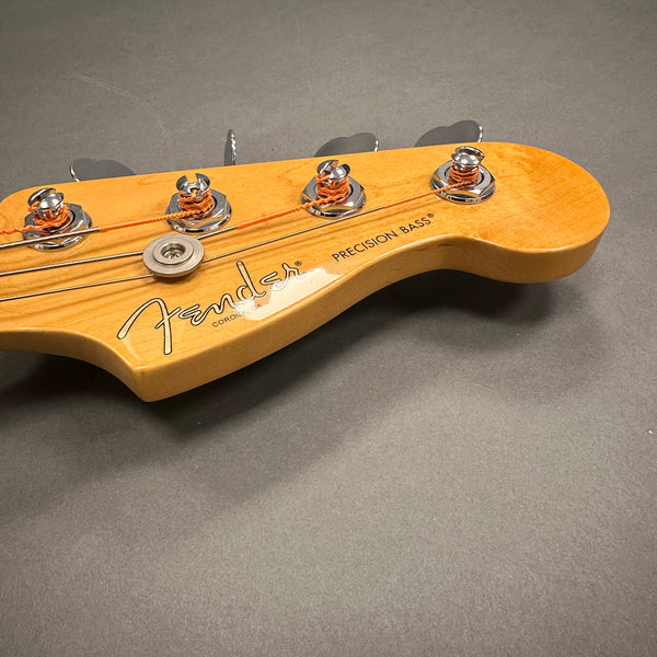 Close-up of Fender Precision Bass headstock with tuning pegs and strings on gray background