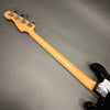 Back view of Fender electric bass guitar with natural maple neck and tuning pegs on gray background