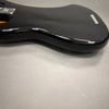 Close-up view of black glossy electric guitar body with contoured edge on gray surface