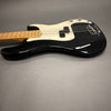 Black electric bass guitar with cream pickguard and maple neck on gray background