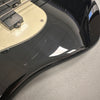 Close-up of black electric guitar body showing scratches and wear near cream-colored pickguard and pickups