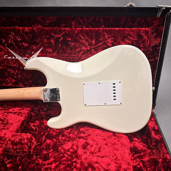 Back view of white Fender electric guitar with maple neck in red plush-lined Fender Custom hard case
