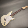Fender Stratocaster electric guitar in vintage white with rosewood fingerboard and three single-coil pickups on gray background