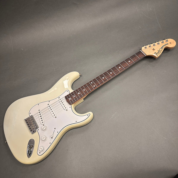 Fender Stratocaster electric guitar in vintage white with rosewood fingerboard and three single-coil pickups on gray background