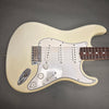 Vintage white electric guitar with three single-coil pickups and white pickguard on gray background