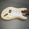 Cream electric guitar with white pickguard and three single-coil pickups on gray background