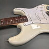Close-up of white electric guitar body and neck with rosewood fretboard and white pickguard on gray background