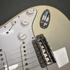 Close-up of white electric guitar body showing tone and volume knobs, pickup selector switch, chrome bridge with Fender branding, and cream pickguard.