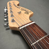 Close-up view of Fender Stratocaster electric guitar headstock with tuning pegs and maple neck on gray background