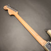 Back view of electric guitar neck with tuning pegs and maple wood finish on gray background