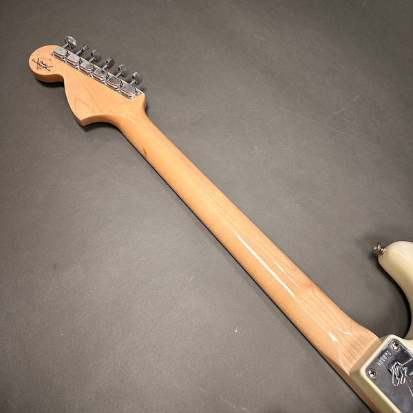 Back view of electric guitar neck with tuning pegs and maple wood finish on gray background