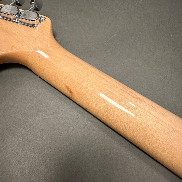 Close-up of a maple guitar neck with a smooth natural finish and chrome tuning pegs on a gray background