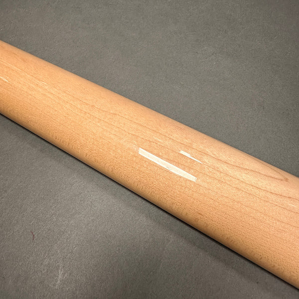 Close-up of a guitar neck with a visible wood grain and a small repair patch on a gray background