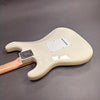 Back view of cream electric guitar body with maple neck and white tremolo cover plate on gray surface