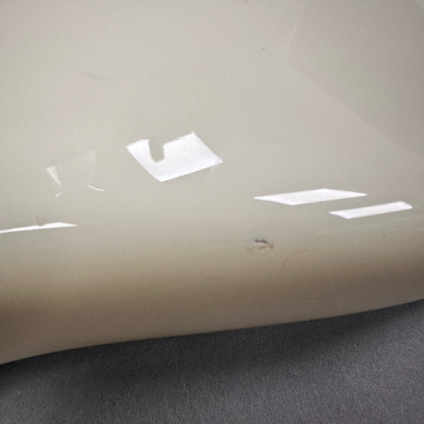 Close-up of cream-colored guitar body with small dent or chip in finish showing minor damage on electric guitar surface