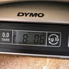Digital scale displaying guitar weight of 8 pounds 0.6 ounces on DYMO brand scale at Coffee House Guitars
