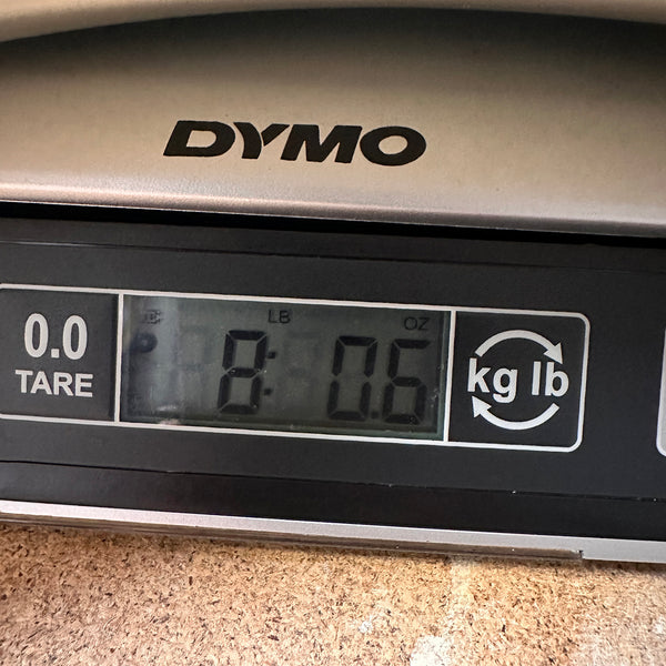 Digital scale displaying guitar weight of 8 pounds 0.6 ounces on DYMO brand scale at Coffee House Guitars